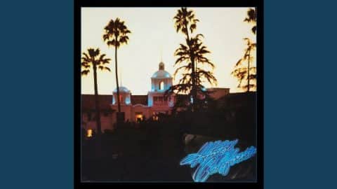 Album cover of ‘Hotel California’ by The Eagles, featuring a warm sunset view of a Spanish-style hotel with palm trees silhouetted against the sky.