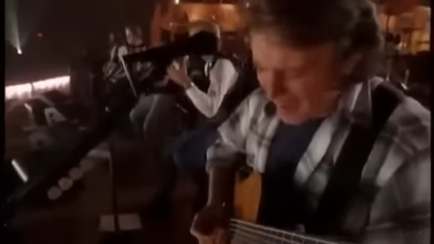 Glenn Frey performing with the Eagles during their Hell Freezes Over reunion concert, captured mid-song with acoustic setup on stage.