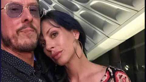 Scott Shriner and Jillian Lauren pose together in a close-up selfie under a geometric ceiling.