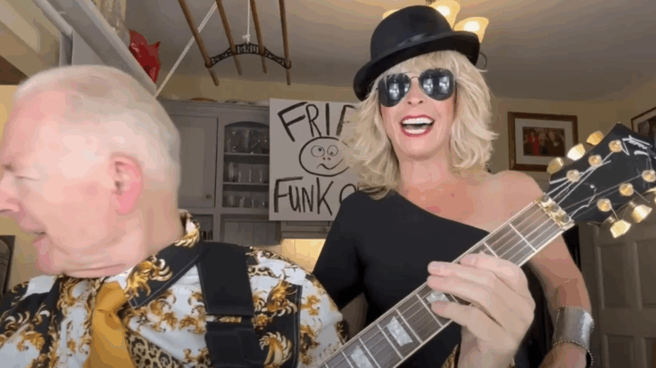 Toyah Willcox sings and smiles in sunglasses and a top hat beside Robert Fripp playing his guitar during their animated cover of