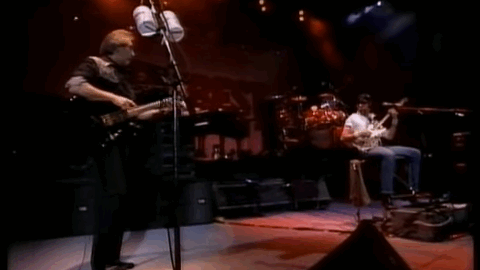 Members of 80s supergroup The Best performing live in Japan in 1990, featuring John Entwistle, Joe Walsh, and other rock legends on stage under colorful lights.