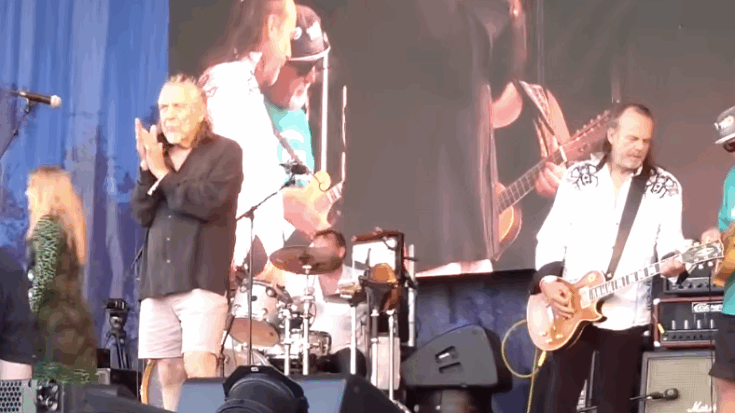 Robert Plant performs alongside the Deborah Bonham Band at the Cropredy Festival, with musicians playing onstage and a large video screen in the background.