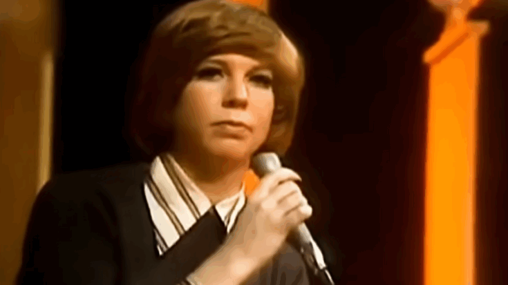 Vicki Lawrence performing “The Night the Lights Went Out in Georgia” on stage in the 1970s, holding a microphone against a warm, orange-lit backdrop.
