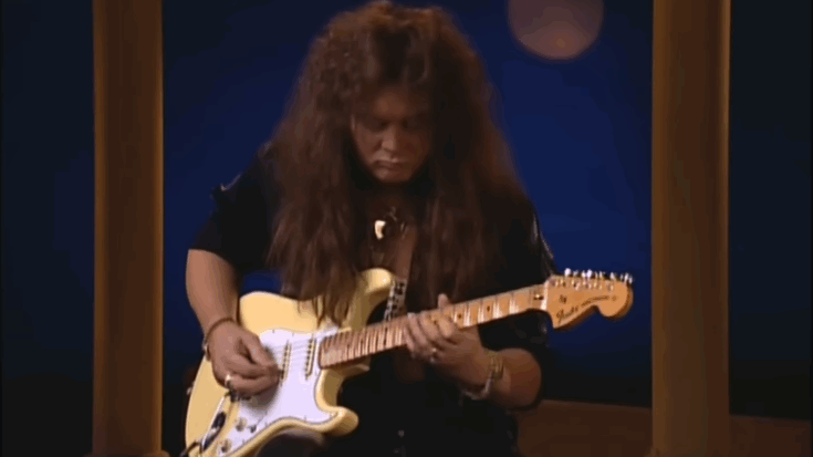 Yngwie Malmsteen playing a white Fender Stratocaster guitar during a live performance of “Far Beyond the Sun.”