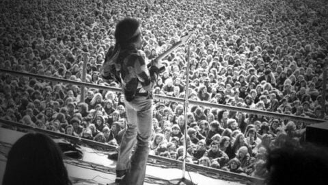 Jimi Hendrix performing live at the Love and Peace Festival in Fehmarn, Germany, 1970, playing guitar before a massive crowd.