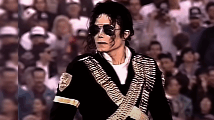 Michael Jackson performing in a black military-style jacket with gold accents in front of a stadium crowd.