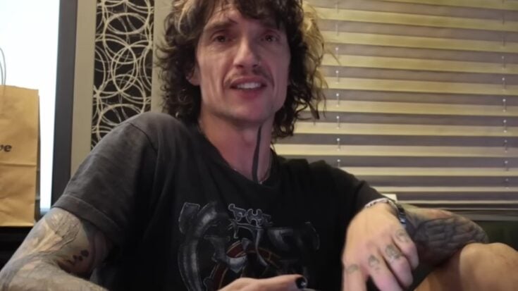 Justin Hawkins of The Darkness sitting casually and speaking in an interview setting.
