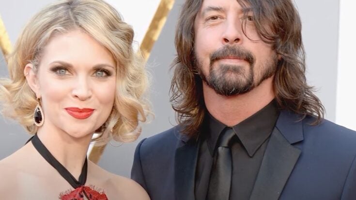 Dave Grohl and his wife Jordyn Blum posing together on the red carpet, captured during a public event.