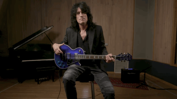 Tommy Thayer sitting in a recording studio holding a blue electric guitar during a reflective moment.