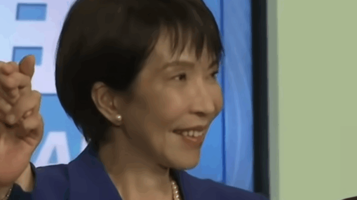 Japan’s new Prime Minister Sanae Takaichi smiling during a public appearance, known for her passion for heavy metal bands like Black Sabbath, Iron Maiden, and Deep Purple.
