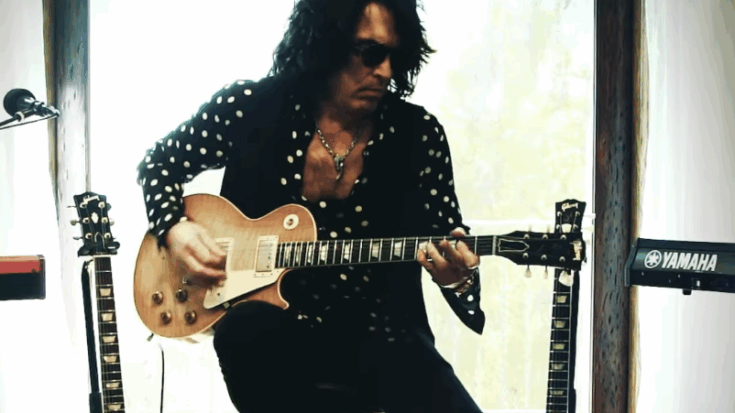 Paul Stanley of KISS playing a gold-top Gibson Les Paul guitar during a studio session, surrounded by other guitars and a Yamaha keyboard.