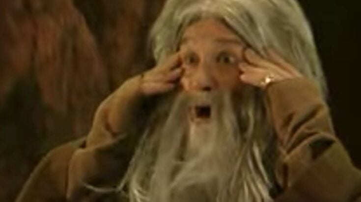 Ozzy Osbourne dressed as Gandalf with a long grey wig and beard, making an exaggerated facial expression during a parody skit.