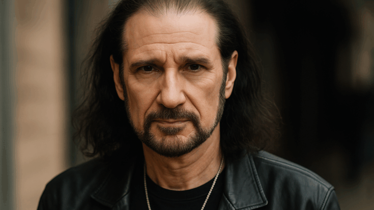 Bruce Kulick photographed in a close-up portrait wearing a black leather jacket, looking directly into the camera.