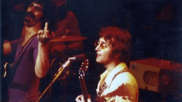 John Lennon and Frank Zappa performing together onstage at the 1971 Fillmore East show, with Lennon at the microphone and Zappa reacting animatedly in the background.